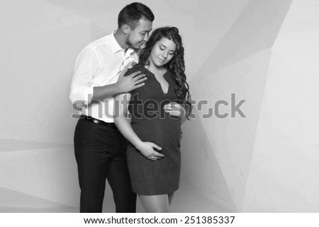 slender man standing embracing his beautiful pregnant wife
