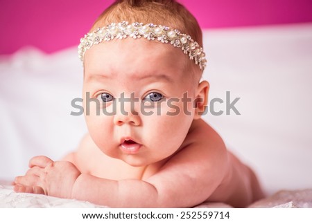 little blue-eyed baby, with an ornament on his head looking at the camera