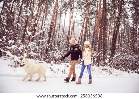boy and girl in winter walks in the woods with a white dog, a lot of snow