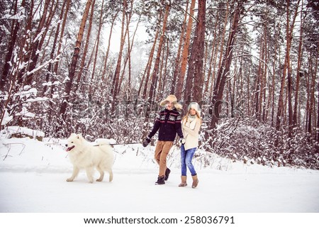 boy and girl in winter walks in the woods with a white dog, a lot of snow