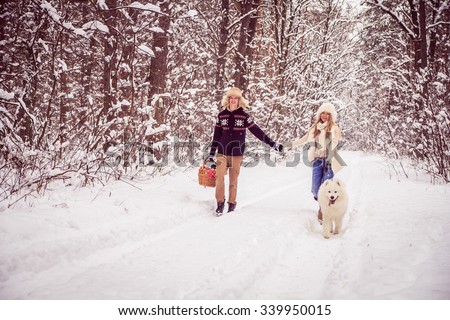 boy and girl holding hands, winter walks in the woods, with a white dog, basket in hand.