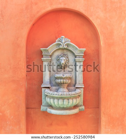 classic stone carved lion heads on orange wall at home