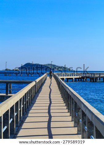 running man with nice view of long cement bridge walk way run on the blue sea with black shadow in blue sky sunshine day