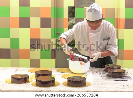 SINGAPORE - JUNE,12: Unidentified woman chef in white uniform prepares  the Chocolate cakes in the colorful kitchen . SINGAPORE JUNE,12 2015