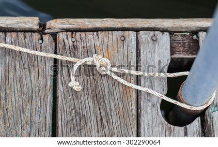 tied rope knot and iron pole on wood floor