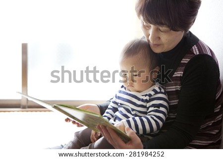 grand mother reading a book to baby