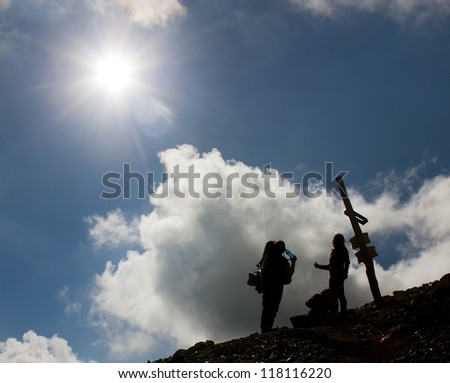 silhouettes of tourists on mountains with sun and beautiful sky