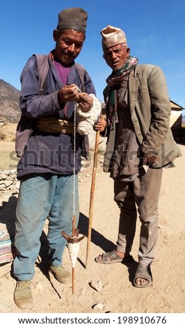 KOLTI VILLAGE, WESTERN NEPAL, 28TH NOVEMBER 2013 - Nepalese who making wool by primitive method during walking