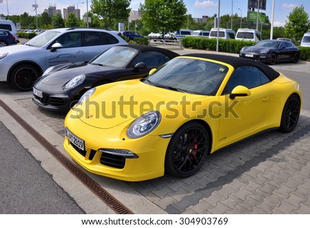 PRAGUE, THE CZECH REPUBLIC, 02.08.2015 - Two Luxury yellow and black Porsche 911 Carrera 4 GTS parking in front of a car store