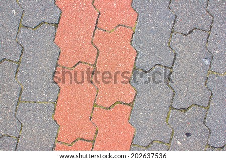 Red brick line dividing gray brick roads.