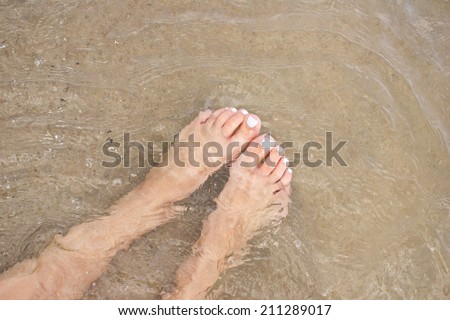 Female feet in water on beach.