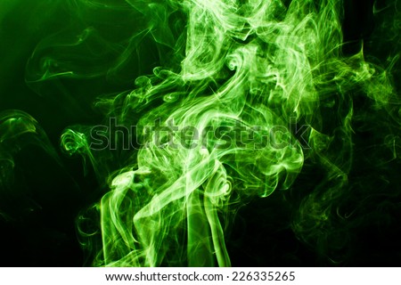 Green and yellow artistic smoke on black background texture.