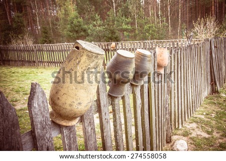 Pottery jars hanging on wooden fence.