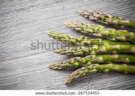Green asparagus on gray wood.