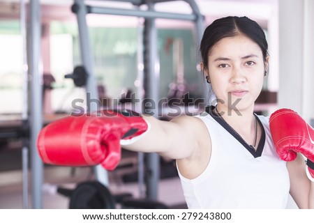 Boxer woman during boxing exercise with red gloves fighting practice throwing aggressive punch training shadow boxing workout in gym.