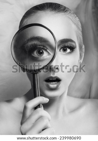 beautiful girl holding a magnifying glass, which increases her eye