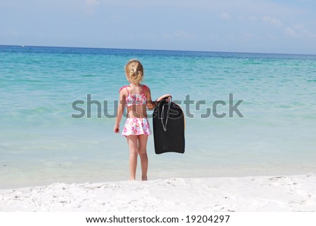 girl on beach in bikini with boogie board.