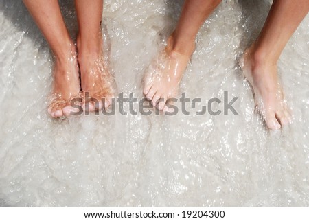 children bare Feet in the ocean on beach