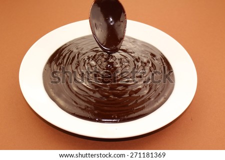 Melted semi-liquid bitter chocolate flowing onto a white plate