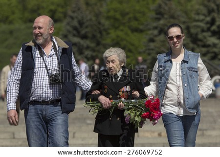 KIEV, UKRAINE - MAY 9 - Unidentified old woman veteran dressed uniform with medals goes with unidentified man and woman sides at Museum of the Great Patriotic War on May 9, 2014 in Kiev.