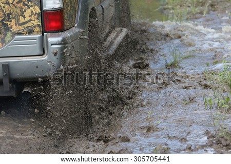 splashes of mud from the wheels while car crosses the swamp