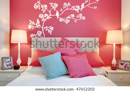 Stylish brightly decorated modern bedroom with wall mural and cushions