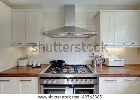 Front on aspect of modern range style cooker with double oven with other kitchen related items standing on a wooden worktop