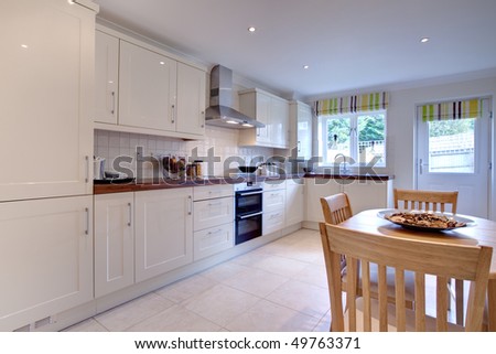 modern stylish kitchen with fitted appliances, table and chairs