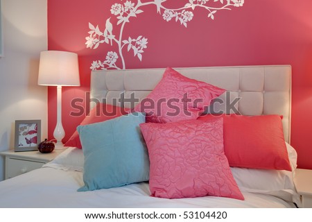 Contemporary bedroom detail with brightly colored cushions and striking pink wall mural