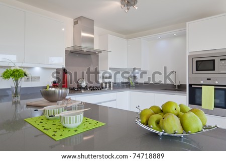 Newly fitted modern kitchen with built in appliances, utensils and basket of fruit