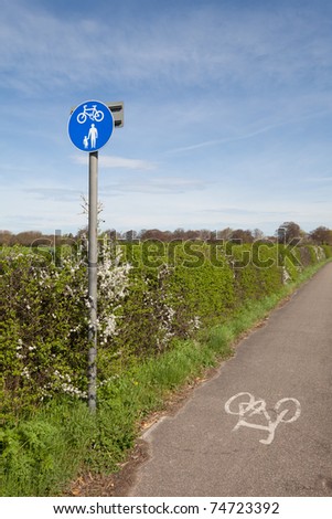 Cycle lane with sign beside a countryside path on a bright day with blue sky and sunshine