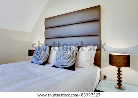 Bed with modern oversize headboard and dressed attractive fabric cushions