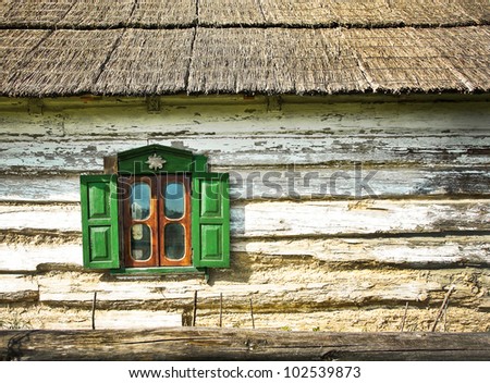 Window with shutters on the facade of an old wooden farmhouse. Country log house with a reed roof - traditional Ukrainian house in the village. Background with old rural chalet and window frame.
