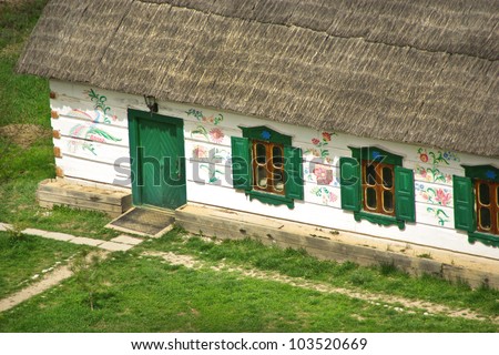 Windows with shutters on the facade of an old wooden farmhouse. Country log house with a reed roof - traditional Ukrainian house in the village. Rural landscape with old chalet.