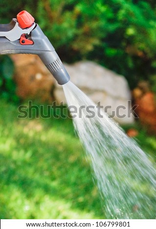 Watering garden equipment - sprinkler hose for irrigation plants. Watering hose and sprayer water on the green grass in summer day.