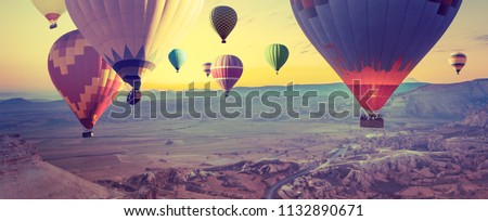 Panorama of Cappadocia at sunrise - multicolored hot air balloons above mountain. Wide landscape of Goreme valley in Turkey - your travel concept in retro style with effect of instagram filters.