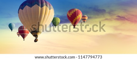 Multicolored hot air balloons at sunset sky for your billboard of a travel agency or wide banner, brigth colors and soft sun light.