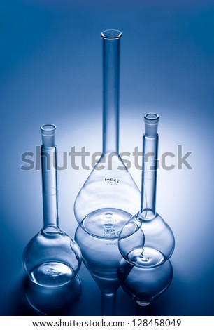 Glass flasks in a chemical laboratory. Scientific equipment for mixing liquids and conducting science experiments and research. Glassware chemistry tools on blue background.