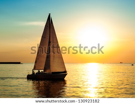 Yacht sailing against sunset. Holiday lifestyle landscape with skyline sailboat and sunset silhouette. Yachting tourism - maritime evening walk. Romantic trip on luxury yacht during the sea sunset.