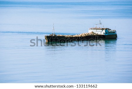 Industrial vessel - bulk-carrier on sea background. Cargo ship sailing with sand heaps.