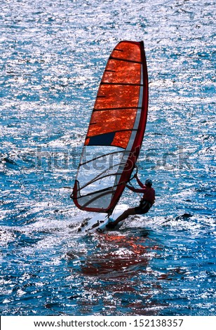 Windsurf - sailing water sports for active leisure. Surfboard with seaside in summer time. Sailboard of windsurfing in sea waves. Windsurfer in action at sea background on sunny day.