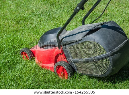 Modern lawn mower on a green lawn. Mowing the lawn with an electric mower with a container to collect the cut grass.