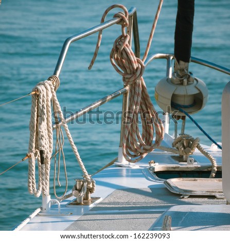 Nautical details on ship deck with ropes and marine tools equipping. Ropes on classic sailboat - tackles on the yacht. Cruising yacht exterior - up of the deck, captain\'s cabin, portholes and mast.