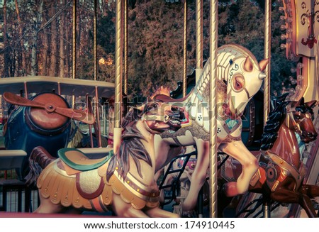 Old French carousel in a holiday park. Three horses and airplane on a traditional fairground  vintage carousel. Merry-go-round with horses.