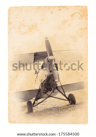 Retro aviation concept - travel landscape with biplane. Old airplane at the airfield. Retro image of the old aircraft on paper texture. Vintage background with airplane of the grunge style.