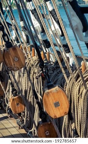 Marine ropes and tackles on the tall ship from sea journey. Rigging details on mast of the old sailboat. Old wooden block with rope on the sail. Marine pulley closeup on the old vessel.
