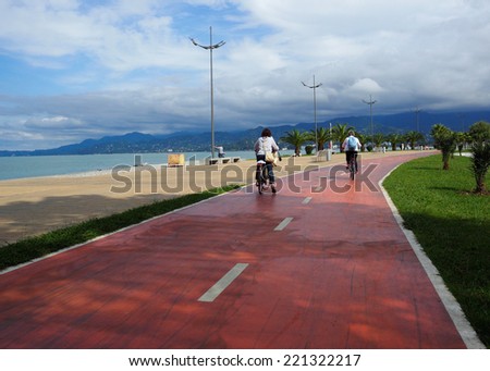 Urban lifestyle - couple biking at red lane. Bicycle lanes on the beach. Bicycle ride along the coast, healthy lifestyle while relaxing at the resort. Bicycling - ecological transport in the city.
