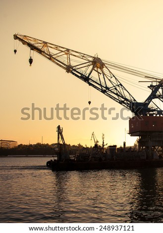 Construction works in the sea at sea platform with a floating crane. Skyline with silhouette of marine crane platform in pier. Industrial landscape - sea port at sunset.