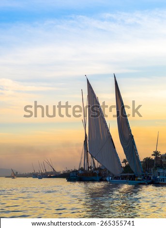 Felucca - traditional sail vessel on Nile river in Egypt. Romantic trip on egyptian boat at sunset. River cruise on the Nile.