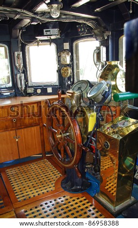 Ship control bridge interior. Wooden captains helm and navigation equipment on the old  sail vessel. Navigator cabin with navigation instruments, rudder and compass.